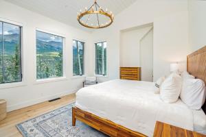 a bedroom with a bed with a chandelier and windows at Overlook House home in Telluride