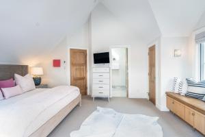a white bedroom with a bed and a dresser at 330 W Pacific B townhouse in Telluride