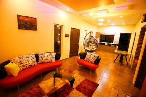 un salon avec un canapé rouge et deux chaises dans l'établissement Habib Villa Tulips, à Ooty