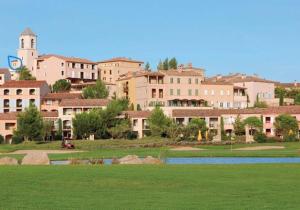 um grupo de edifícios com um campo verde e uma cidade em Appartement vue panoramique au domaine et golf de pont royal em Mallemort