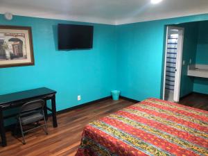 a bedroom with a bed and a desk and blue walls at Star Motel in Norwalk