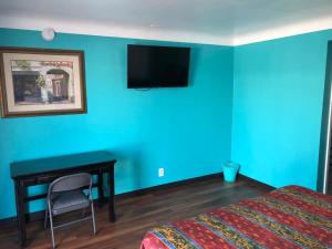 a bedroom with a blue wall with a bed and a desk at Star Motel in Norwalk