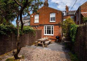 a patio with a wooden table in front of a brick house at Bay House in Southwold
