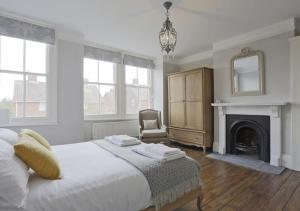 a white bedroom with a bed and a fireplace at Bay House in Southwold