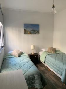 ビセンテ・ロペスにあるSweet Homeのベッドルーム1室(ベッド2台、テーブルの上にランプ付)