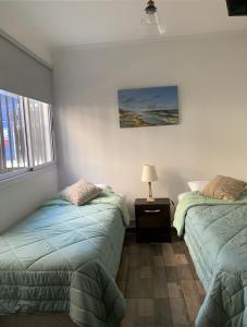 een slaapkamer met 2 bedden, een lamp en een raam bij Sweet Home in Vicente López