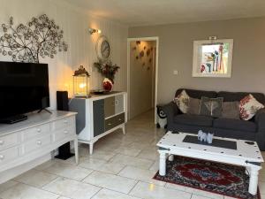 een woonkamer met een bank en een tv bij Pebbles Seaside Lodge in Kent
