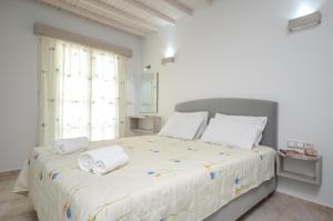 a white bedroom with a large bed with towels on it at Pension Elena in Agia Anna Naxos