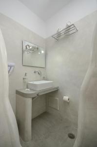 a white bathroom with a sink and a mirror at Pension Elena in Agia Anna Naxos