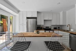 a kitchen with white cabinets and a island with two chairs at Mid-Century Modern Dream Retreat in West Kelowna +9 photos