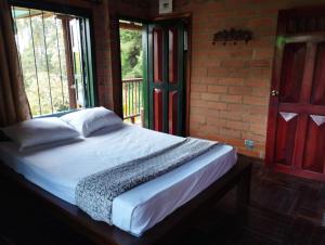 1 dormitorio con cama y pared de ladrillo en Hotel Loma Encantada, Guatapé - Piedra del Peñol, en Guatapé