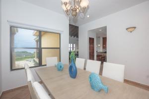 a dining room with a table with a blue vase on it at Pineapple Villa 142 condo in Roatan