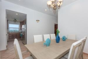 a dining room with a wooden table and white chairs at Pineapple Villa 142 condo in Roatán