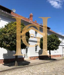 Una casa blanca con una gran señal de oro. en Haus Gitta - Wohlfühlen & Genießen, en Luckenwalde