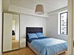 una camera da letto con un letto blu e uno specchio di Demims Apartments Lillestrøm - Modern & Super Central - 10mins from Oslo S a Lillestrøm