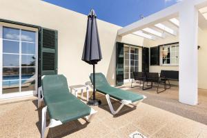 a patio with two chairs and an umbrella at Villa Jordi - Cala en Porter in Cala'n Porter
