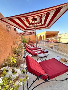 a group of red chairs under an umbrella on a balcony at Riad Shaden in Marrakesh