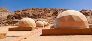 Una fila de cúpulas en un desierto con una montaña en Wadi Rum Marcanã camp en Áqaba