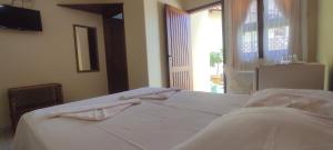 a bedroom with a bed with white sheets and a window at Suítes Jardim dos Sonhos in Ubatuba