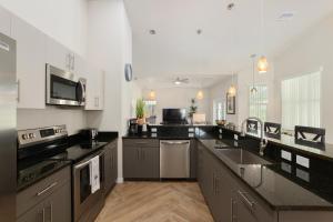 a large kitchen with black counter tops and appliances at Villa Ilse: New Stylish Home With Private Pool in Inverness