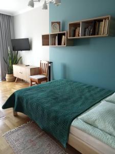 um quarto com uma cama com um edredão verde e uma secretária em Apartament Prowansalski em Gdansk
