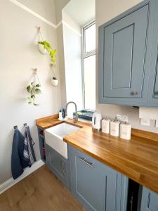 uma cozinha com armários azuis e um lavatório em Lossie Self-Catering Apartment em Lossiemouth