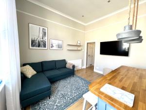 uma sala de estar com um sofá azul e uma mesa em Lossie Self-Catering Apartment em Lossiemouth