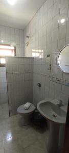 a white bathroom with a sink and a toilet at Suítes Jardim dos Sonhos in Ubatuba