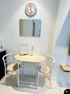 uma mesa e cadeiras com um relógio na parede em Cozy Studio Penthouse I Wi-Fi I Netflix l Pool em Manila
