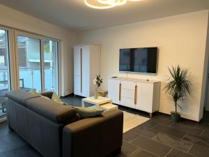 ein Wohnzimmer mit einem Sofa und einem Flachbild-TV in der Unterkunft Modern Apartment Mainz by PMA in Mainz