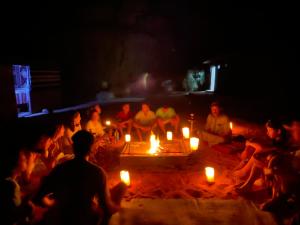 Un gruppo di persone sedute intorno al fuoco con le candele di Bedouin Memories Camp a Wadi Rum