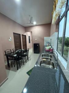 a kitchen with a sink and a table with chairs at Homestay Taman Hidayah Chawas in Tanah Merah