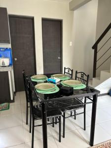 a black table with chairs and plates on it at 1BR Townhouse + Netflix in Marilao