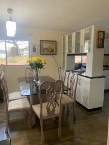 a dining room with a table and chairs and a kitchen at Los Quillayes in Melipilla