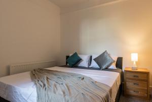 a bedroom with a bed with blue pillows and a lamp at Quality Stay Room in Brighton & Hove