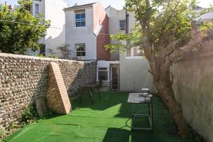 a small yard with a brick wall and green grass at Quality Stay Room in Brighton & Hove