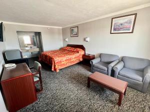 a hotel room with a bed and two chairs and a table at Hotel 81 El Reno in El Reno