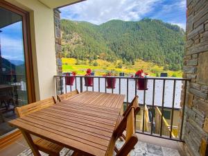 a wooden table and chairs on a balcony with a view at 3 Hab en Arinsal a PIE DE PISTAS - Terraza con Vistas - 1 plaza Parking Incluido in Arinsal