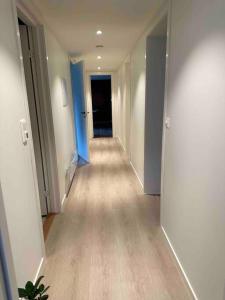 an empty hallway with blue walls and wooden floors at Nyoppusset og romslig leilighet med 6 soveplasser i et familievennlig område in Sarpsborg