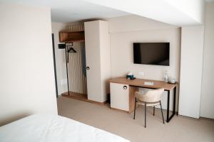 um quarto com uma secretária, uma televisão e uma cama em River Park Hotel em Drăgăşani