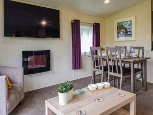 a living room with a table and a tv at Glenbeagles Lodge in Dollar