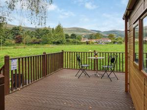 a wooden deck with a table and chairs on it at Glenbeagles Lodge in Dollar