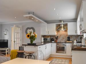 a kitchen with white cabinets and a vase of flowers at Folly Lodge in Sewerby