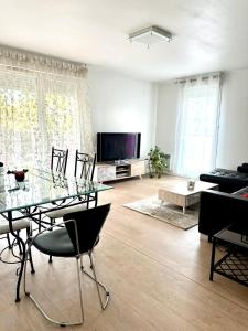 a living room with a glass table and chairs at BIG logement , JO2024, stade de France, PARIS, métro , parking gratuit in Saint-Denis
