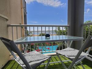 een balkon met een glazen tafel en 2 stoelen bij Au bord de la plage du Grazel in Gruissan