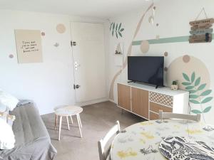 een woonkamer met een tafel en een televisie bij Au bord de la plage du Grazel in Gruissan