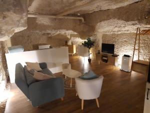 a living room with a couch and chairs and a tv at La Grotte du Bonheur in Cangey