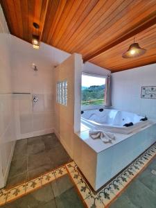 a large bathroom with a tub and a window at Pousada Vale das Araucárias in Santo Antônio do Pinhal