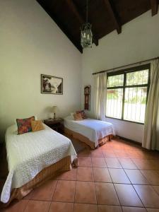 a bedroom with two beds and a large window at Casa San Miguel in Antigua Guatemala