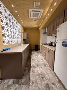 Il comprend une grande cuisine équipée d'un réfrigérateur blanc et de placards. dans l'établissement شاليه غرناطة, à Al Khabrāʼ